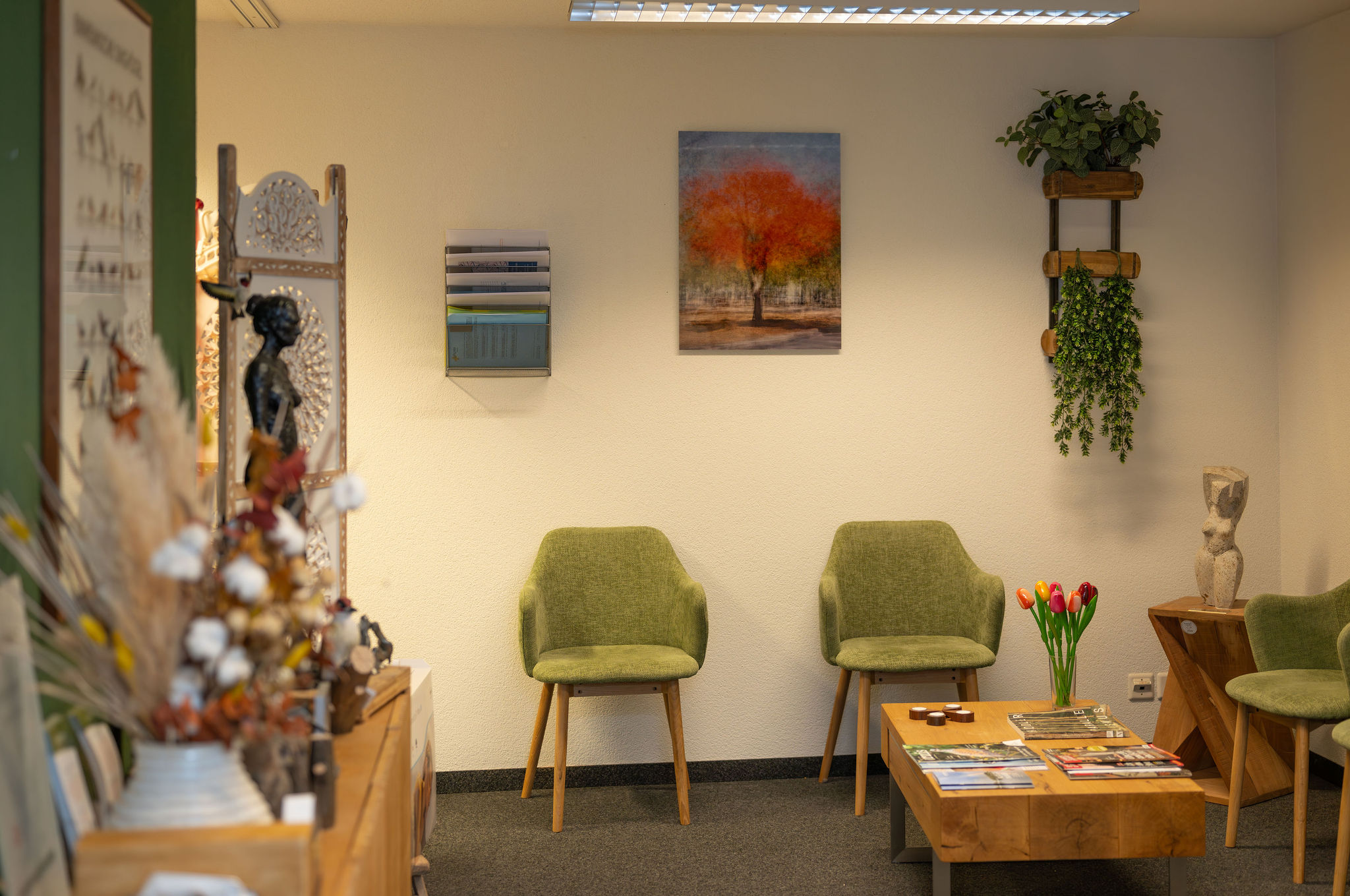 Gemütliches Wartezimmer der Physio Kinetic Praxis in Fehraltorf mit grünen Stühlen und Pflanzen